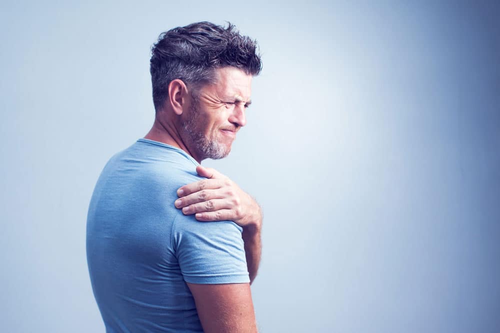 Man suffering from neck or shoulder pain at home